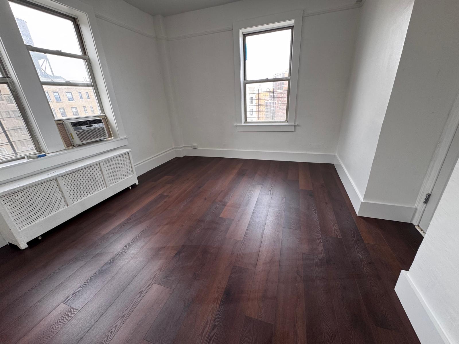 Completed apartment room with clean walls, refinished floor and new window trim