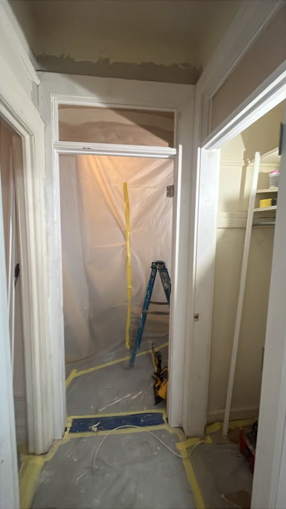 Apartment corridor protected with floor covering, taped seams and a plastic containment barrier