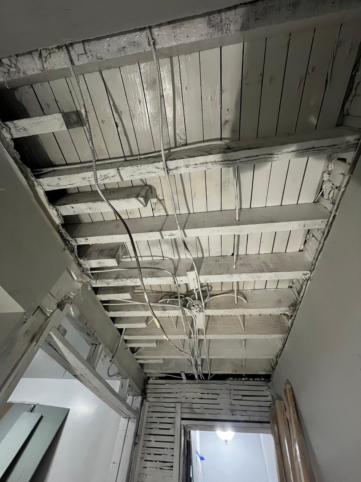 Opened plaster ceiling exposing framing and wiring during controlled remediation work