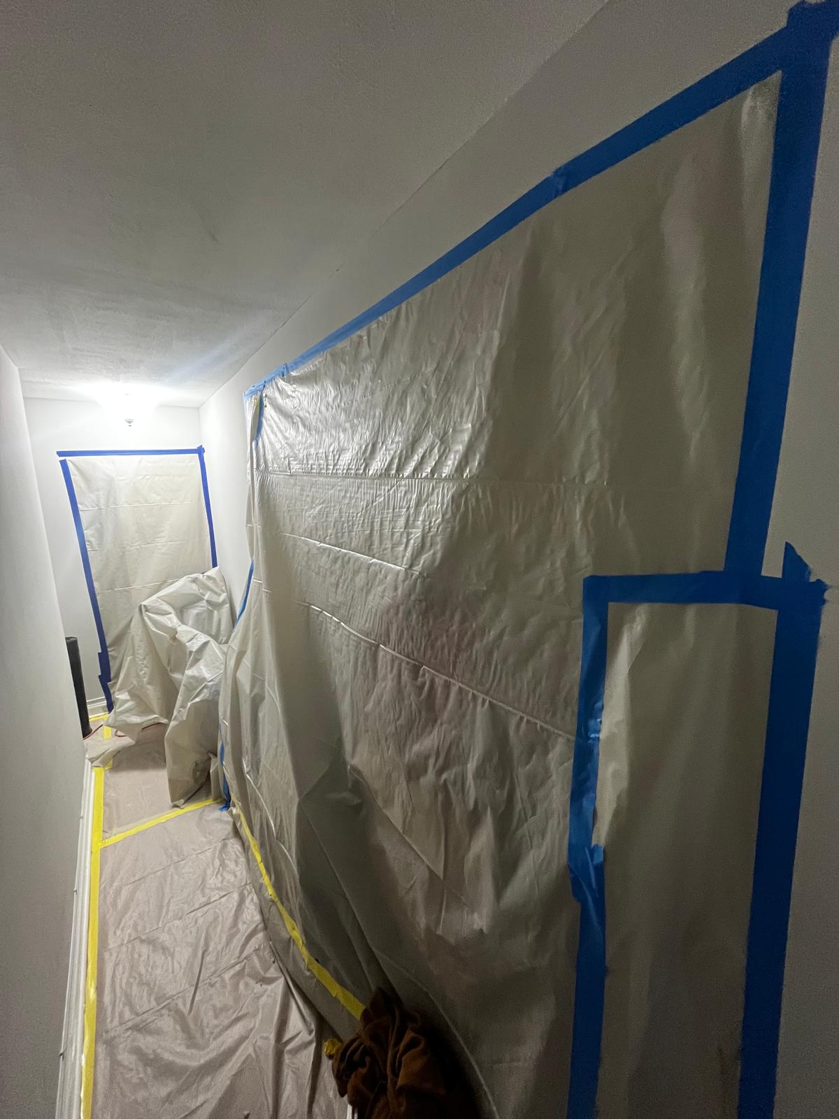Apartment hallway isolated with taped plastic sheeting during abatement work