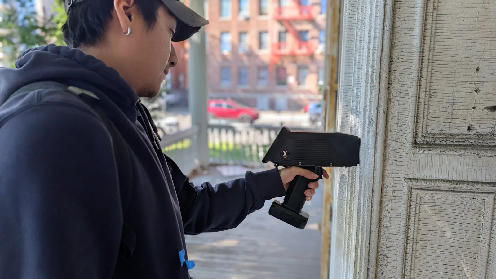 Manhattan Lead inspector holding an XRF analyzer against painted door casing on an older building