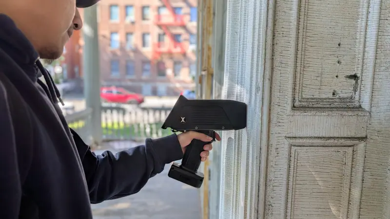 Handheld XRF analyzer taking a lead paint reading on a painted wood door panel