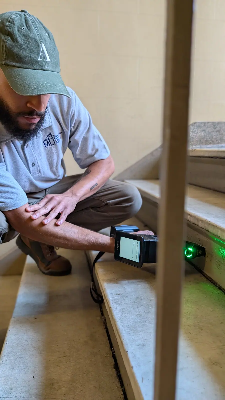 Inspector crouching in a stairwell scanning the steps with a handheld XRF analyzer