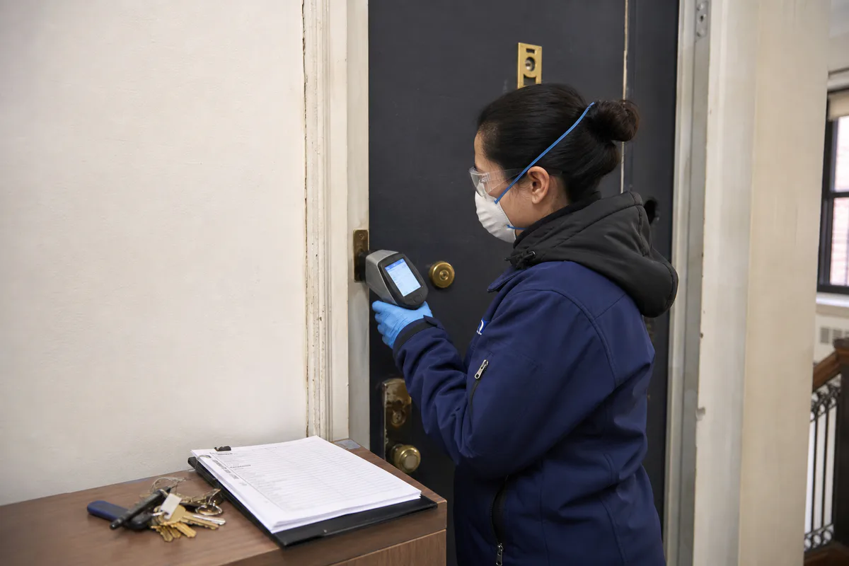 Certified inspector taking an XRF reading on an apartment door friction surface