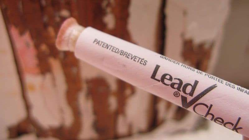 Lead test swab held against rusted peeling paint